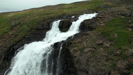 revealing droneshot of a waterfall that flows deep into a valley