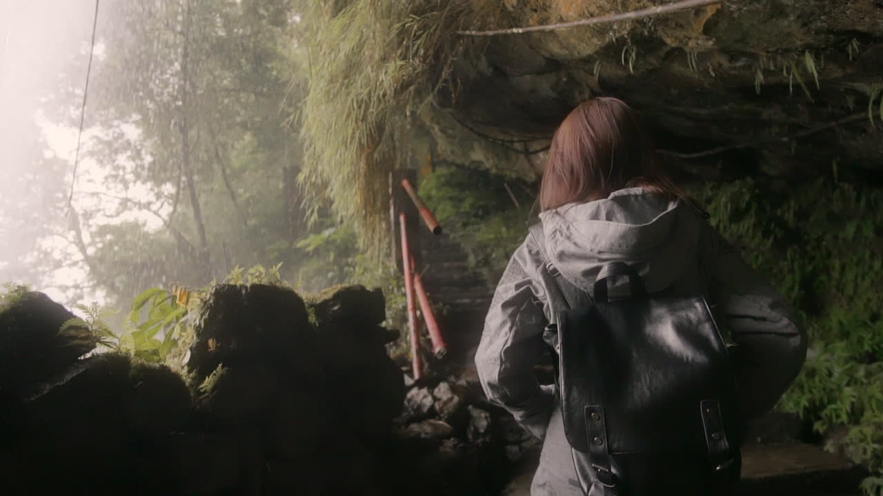 Girl walking under waterfall in Taiwan