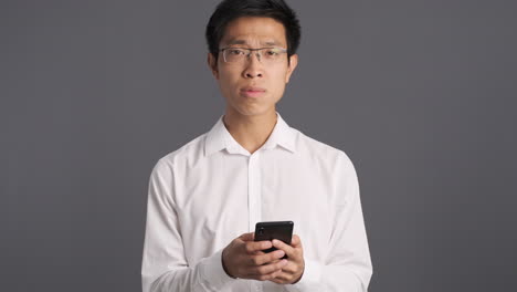 asian man using smartphone getting annoyed.