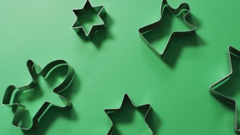 Angel,-gingerbread-man-and-star-shaped-cookie-cutters-and-copy-space-on-green-background