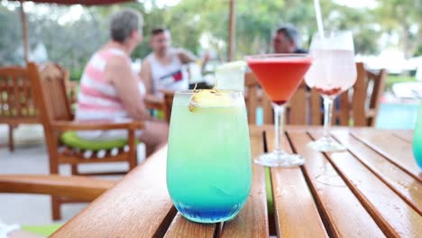 stirring a blue cocktail on an outdoor table