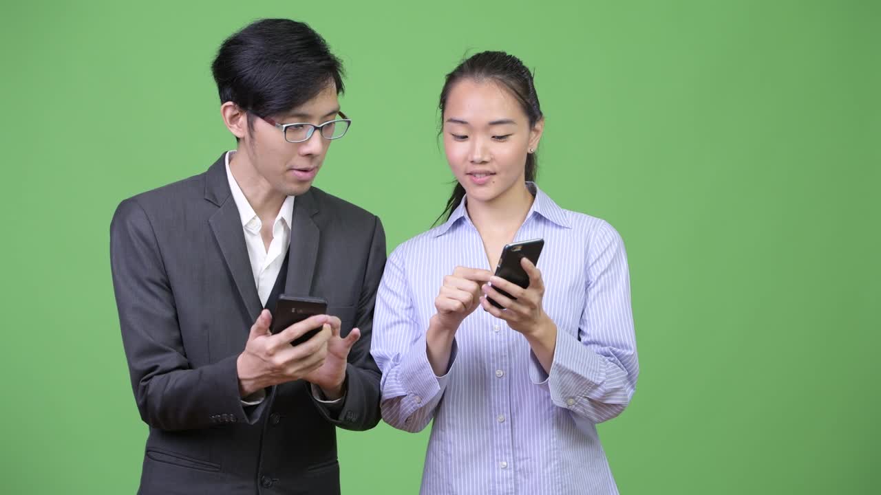 Young Asian business couple using phone together