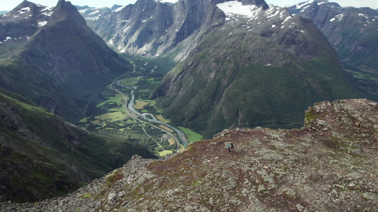 dos excursionistas se alejan del borde de una impresionante cresta impresionante en noruega, romdalseggen, vista aérea