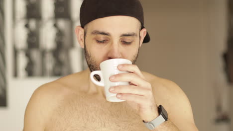 smiling caucasian man drinks a cup of tea or coffee indoor