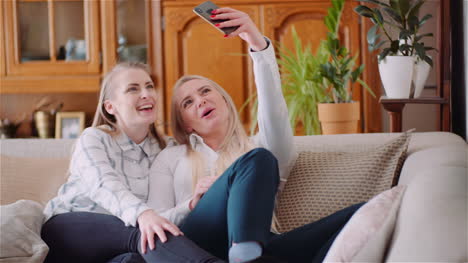 dos mujeres enérgicas positivas tomando una foto selfie en un sofá en una lujosa sala de estar moderna 5