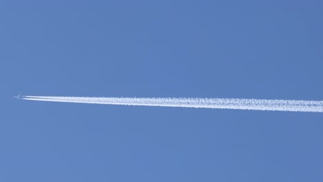 a jet plane leaves a distinct contrail across a clear blue sky, showcasing high-altitude flight dynamics.