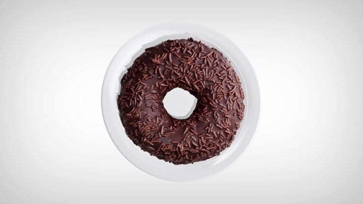 Delicious chocolate donut rotating on a white plate. Donut close-up. Top view