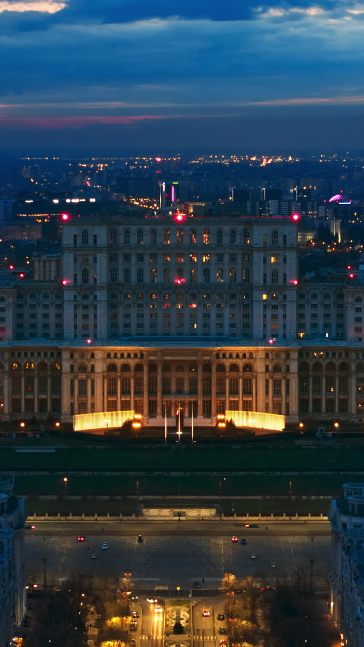 Vertical aerial hyperlpase timelapse drone view of illuminated Palace of the Parliament in Bucharest downtown in the evening. Multiple districts around. Romania