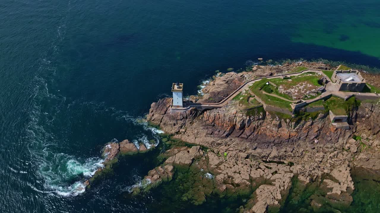 Kermorvan lighthouse and fort on rocky peninsula in Le Conquet, surrounded by deep blue sea, Brittany, France. Aerial top-down orbiting