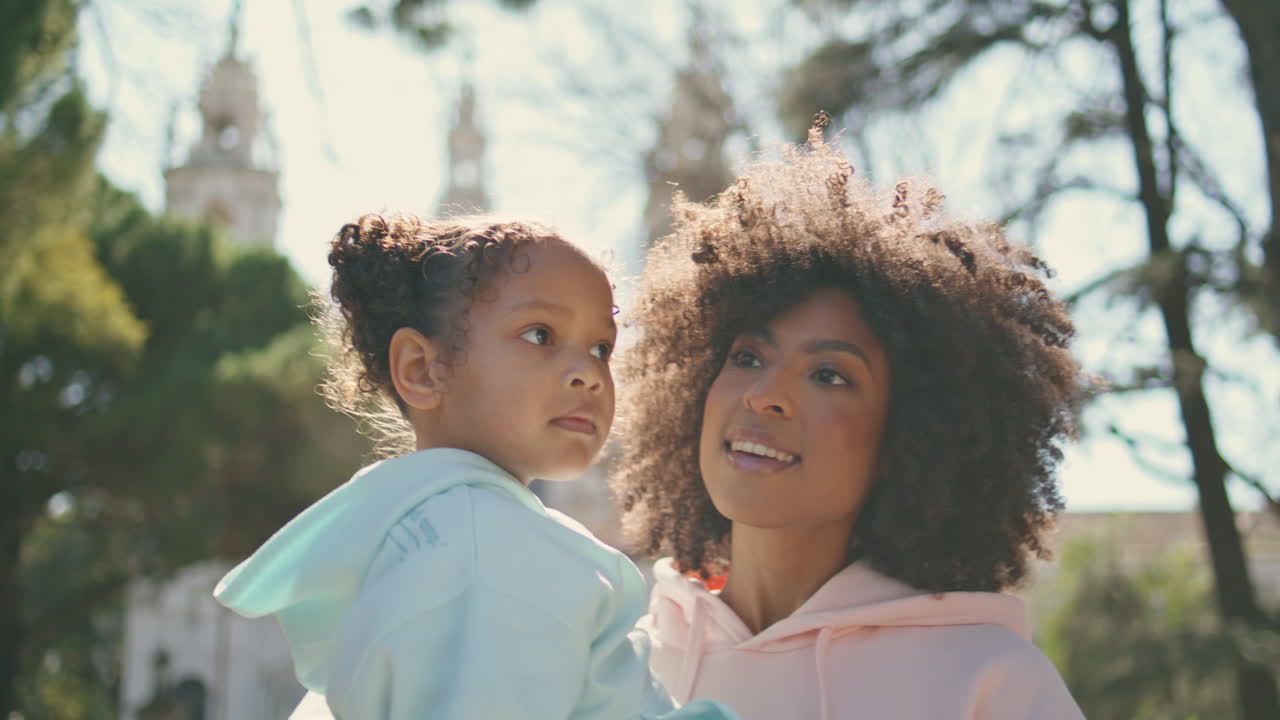 madre llevando a su hija caminando por el parque soleado de cerca. fin de semana familiar.