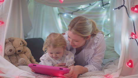 Mother-and-young-daughter-with-digital-tablet-in-homemade-camp-in-child's-bedroom-at-home---shot-in-slow-motion