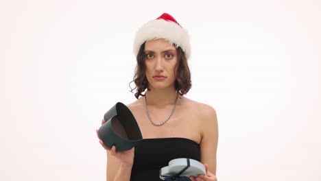 woman in santa hat looks disappointed with an empty heart-shaped gift box