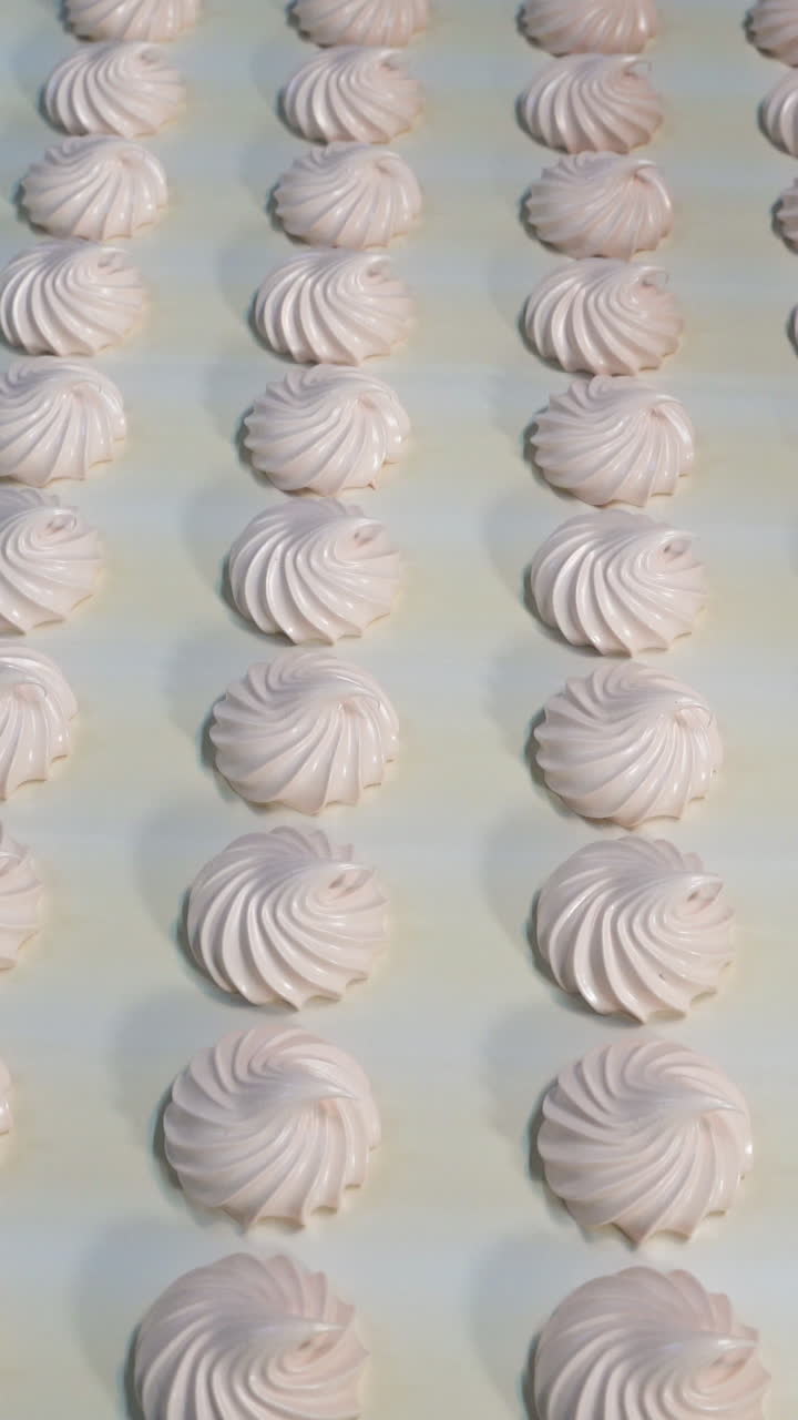 Sweet tender marshmallow moves on a conveyor belt. Automatic sweets production line at a candy factory. Vertical video