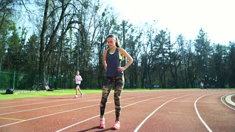 young fitness woman runner stretching legs on stadium track