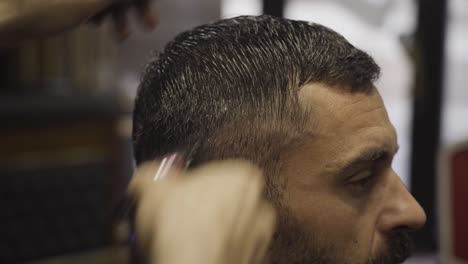 vista lateral de un hombre que se corta el cabello en una barbería