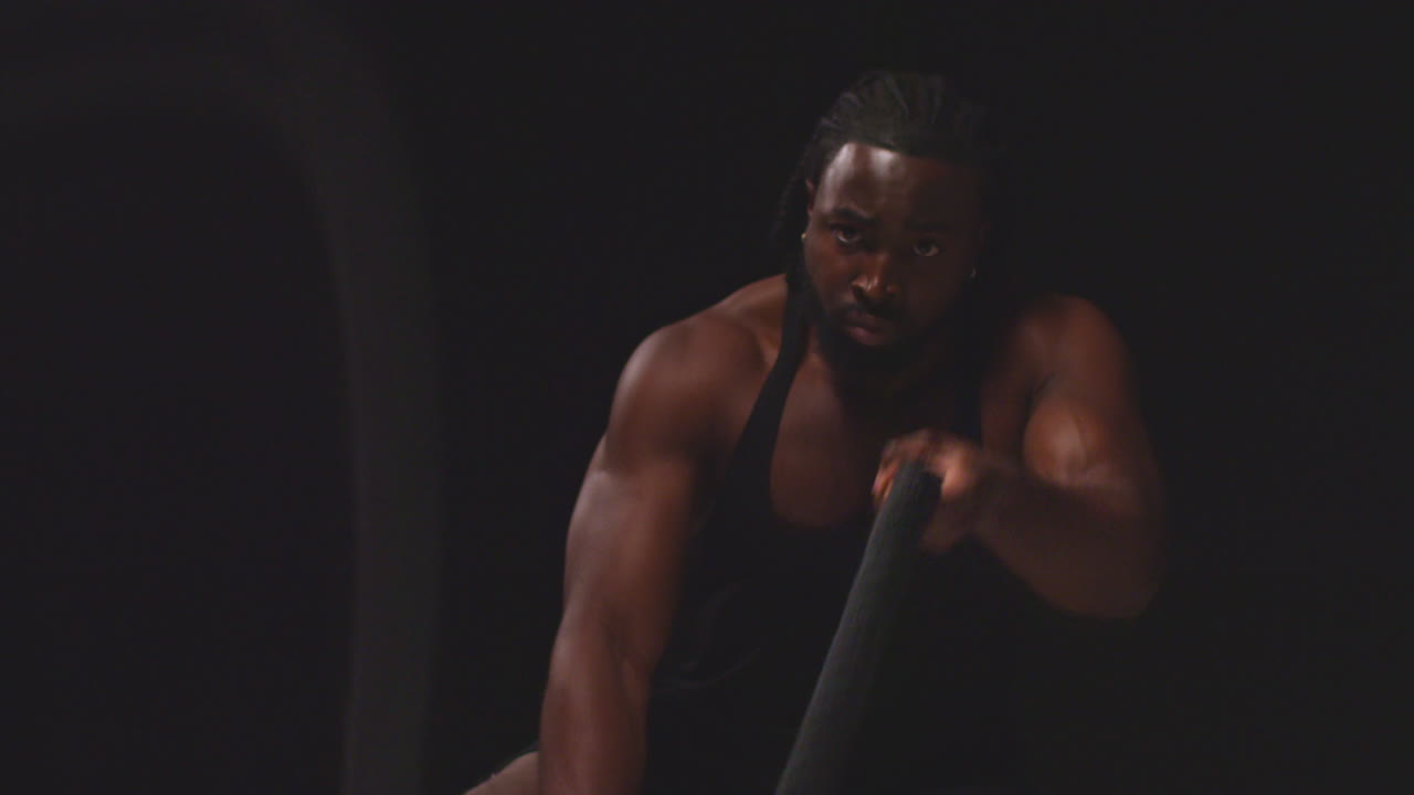 검은 바탕에 찍은 전투 로프를 사용하여 베스트를 입고 훈련하는 남성 운동 선수의 스튜디오  1