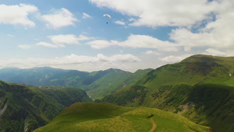 wide drone shot of a paraglider in the caucasus mountain range in gudauri georgia