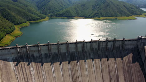 panoramic view of a massive concrete dam and reservoir among green mountains