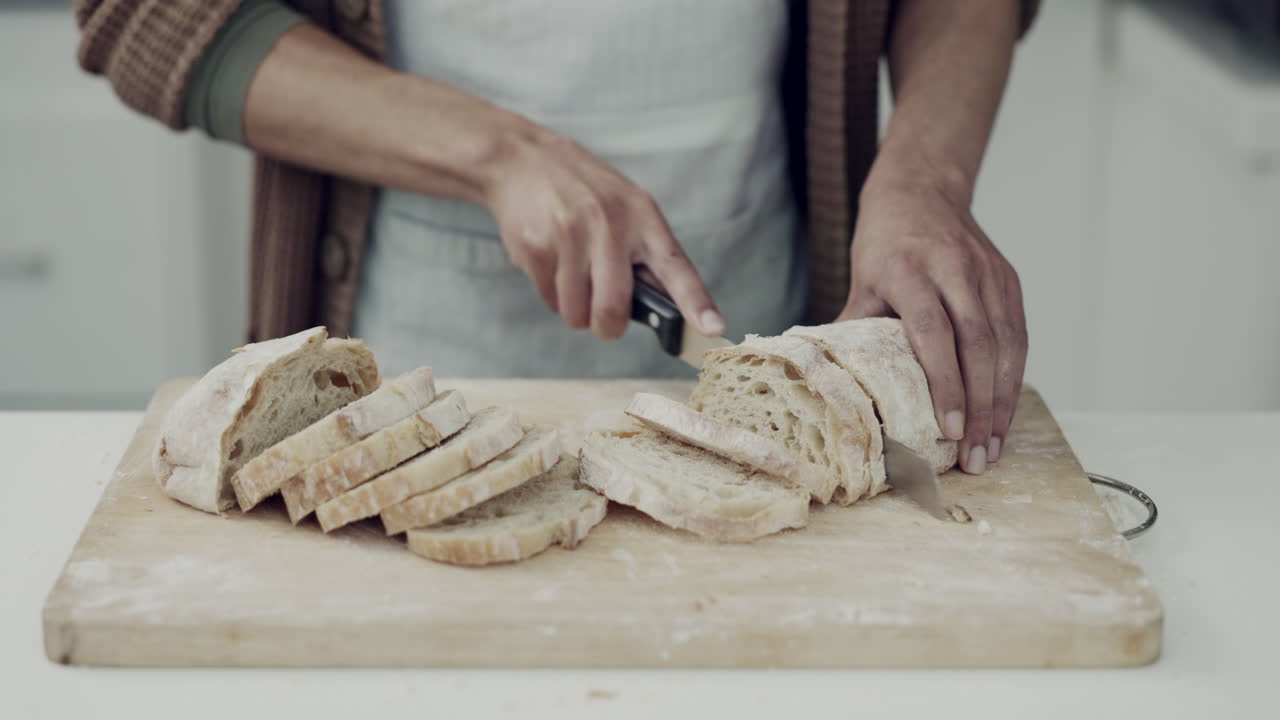 Bread, knife and hands of person in kitchen