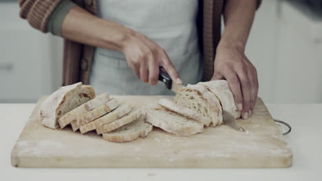 Bread,-knife-and-hands-of-person-in-kitchen