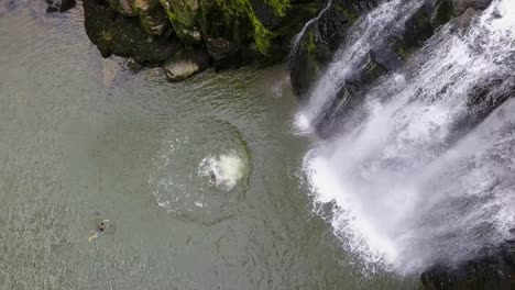 Young-acrobat-jumping-from-a-cliff-near-a-waterfall,-in-the-Doubs-river,-Switzerland