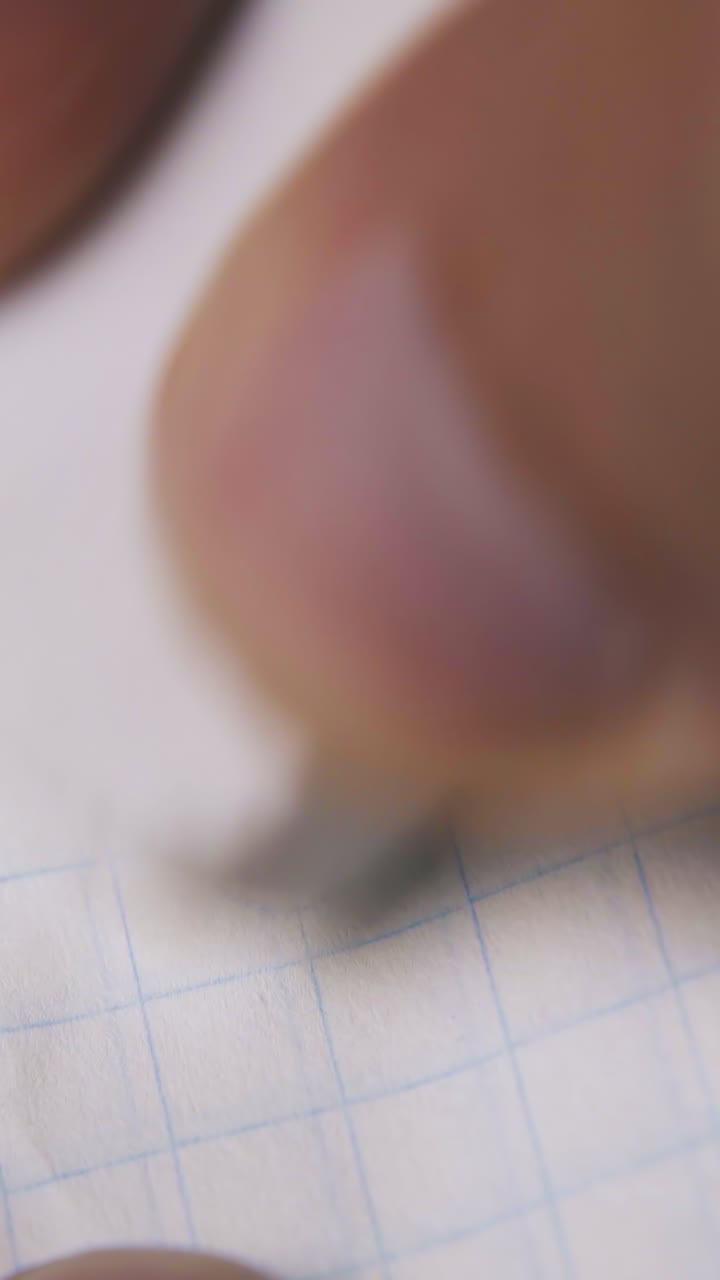 man fingers use white rubber eraser to remove face picture from checkered paper extreme close view