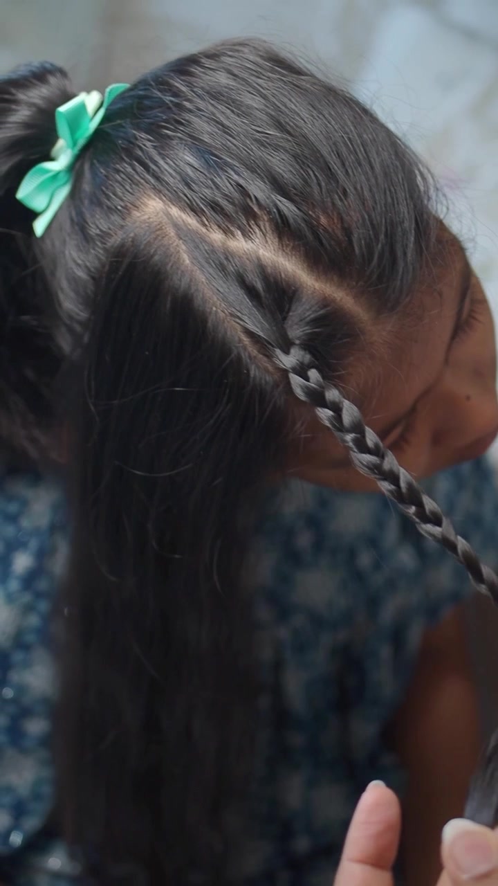 Mother Braiding Her Daughter's Hair at Home