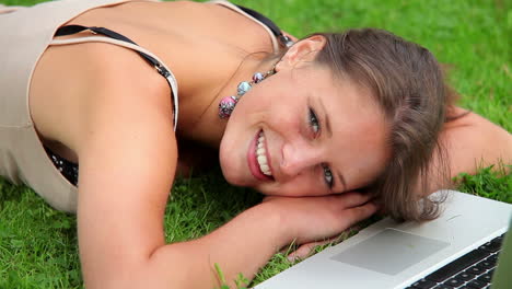 happy student sleeping on grass in front of laptop