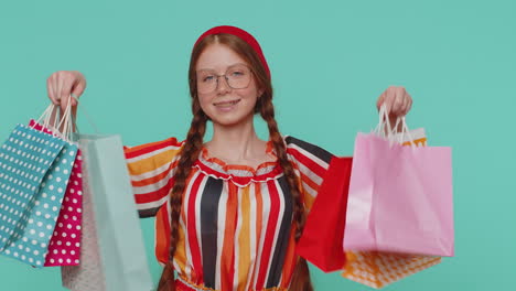 chica pelirroja mostrando bolsas de compras, anuncios de descuentos, sonriendo mirando asombrado con los precios bajos