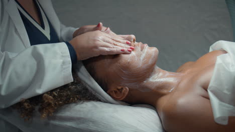 beautician doing facial massage after peeling closeup. hands touch patient skin