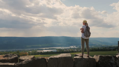 Die-Reisende-Steht-Vor-Dem-Hintergrund-Des-Epischen-Himmels-Unten-Ist-Der-Fluss-Und-Die-Stadt