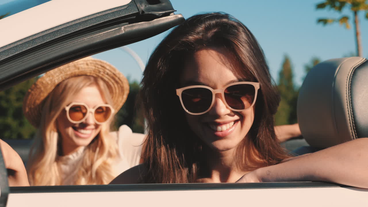 dos mujeres disfrutando de un viaje por carretera de verano en un descapotable