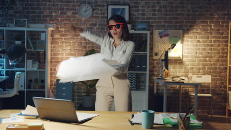 woman throwing papers in office at night