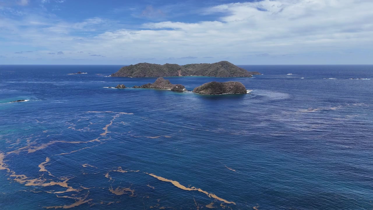 Vista aerea di Goat Island e Little Tobago viste dalla costa di Speyside. Profonde acque caraibiche turchesi circondano isole rocciose vulcaniche sotto un cielo estivo luminoso a Tobago