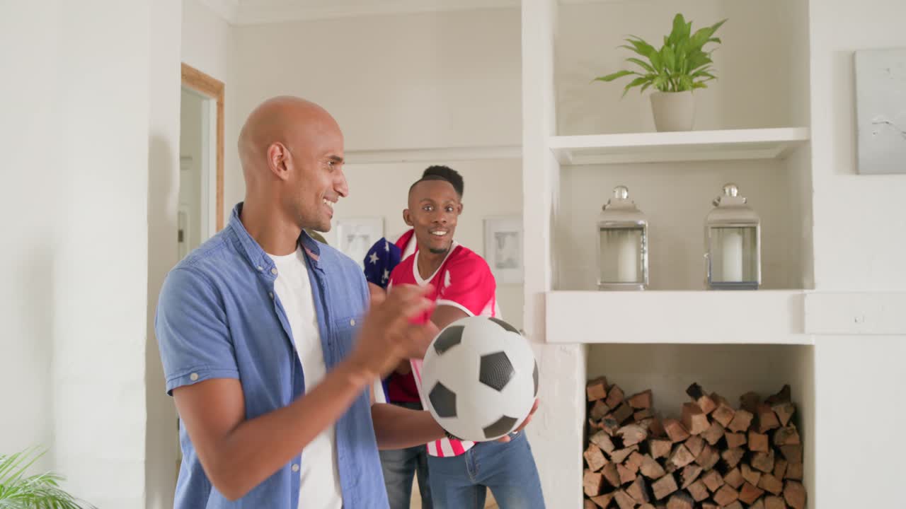 Diverse casual male friends entering home holding soccer ball and sixpack, greeting before game