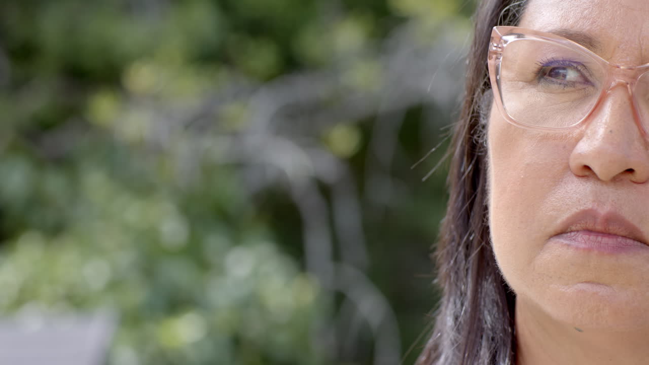 Wearing glasses, elderly woman looking thoughtful and focused in garden, copy space