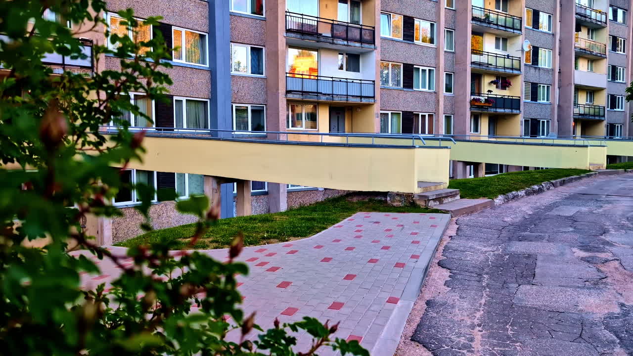 Obytný bytový dům s balkony a záře večerního slunce.