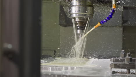 active cnc machine tool with cooling liquid stream and metal shavings during operation