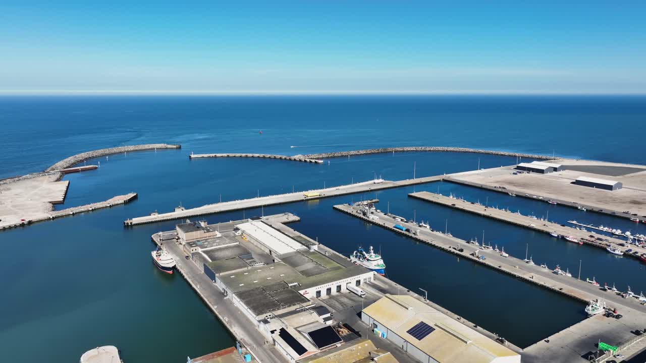 A clear daytime drone shot of Port Hanstholm in Denmark, featuring the bustling pier, calm waters, and surrounding coastal scenery—a perfect blend of maritime life and natural beauty.