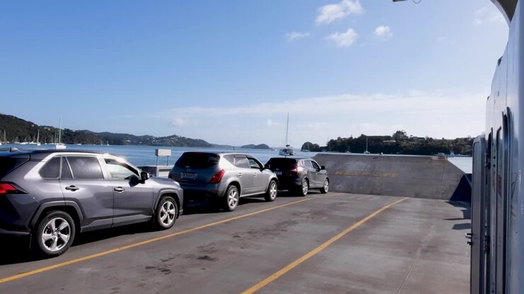 Vehículos aparcados en el transbordador de pasajeros y coches cruzando a la ciudad de Okiato, Old Russell en la Bahía de las Islas, Nueva Zelanda Aotearoa