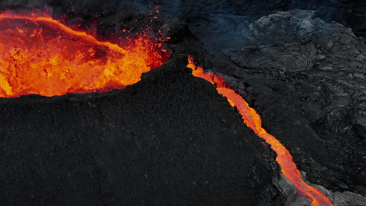 Vulcano in eruzione, magma che schizza fuori da un cratere creando colate di lava, primo piano da drone.