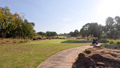 un carro de golf viaja a lo largo de un camino soleado