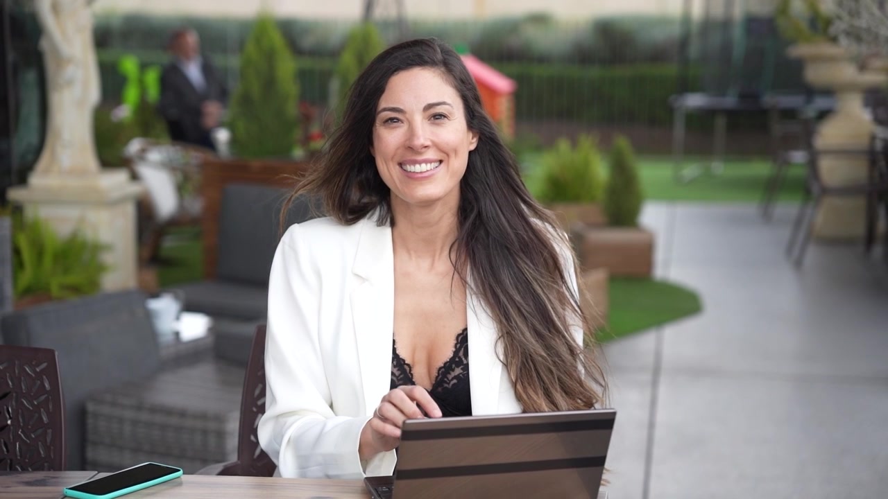 Empresaria profesional trabajando al aire libre con su portátil y una taza de café caliente.