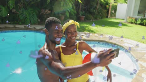 Animation-of-media-icons-over-happy-african-american-couple-taking-selfie