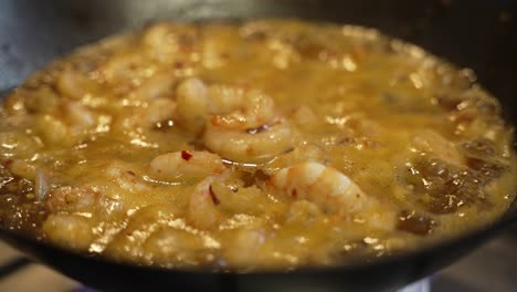langostinos en salsa burbujeante hirviendo a fuego lento dentro del wok