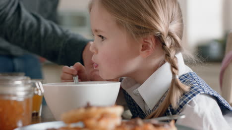 beautiful little girl eating breakfast cereal in kitchen father preparing daughter for school in morning