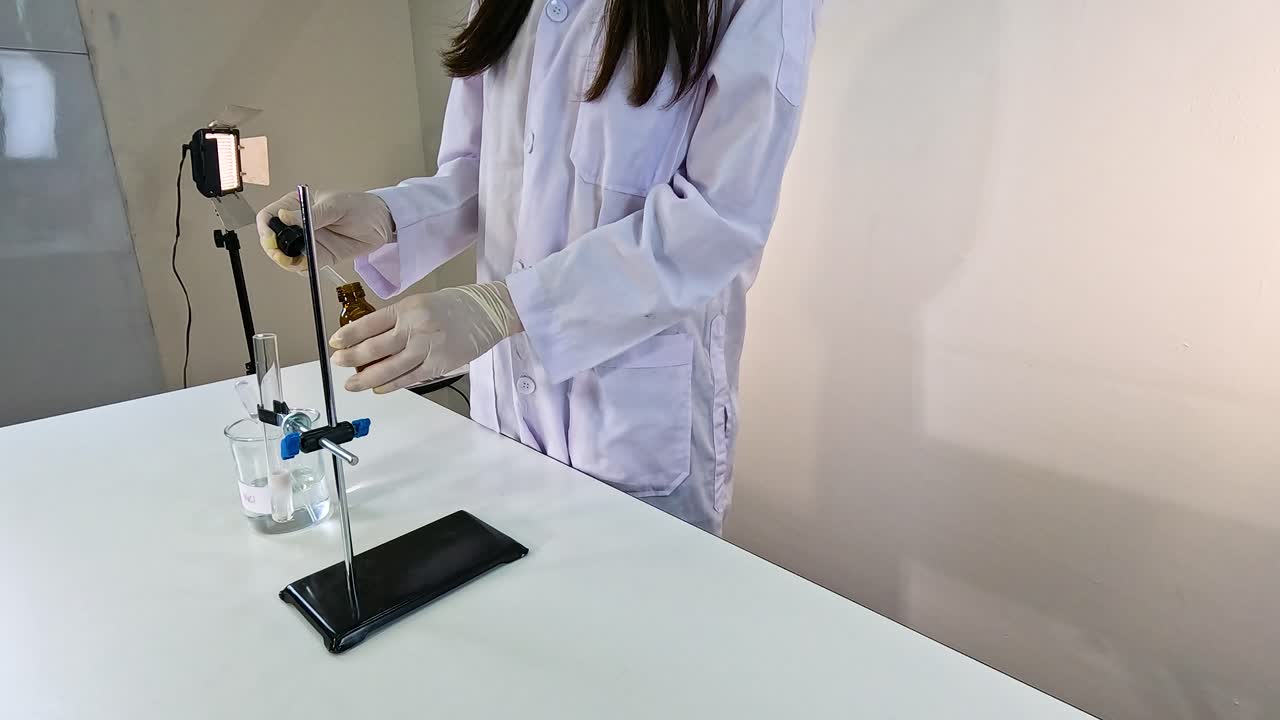 Scientist conducts a chemical reaction using lead nitrate and potassium iodide in a laboratory setting with controlled lighting