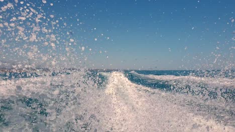 low angle pov of motor boat wake trail and water spray on sea surface