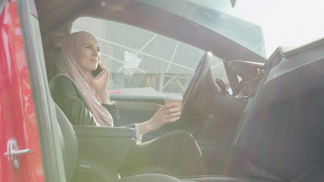 businesswoman driving an electric car, talking on the phone, and drinking coffee.