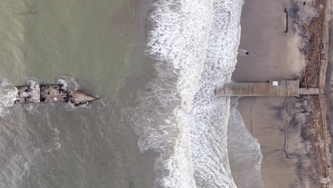 Boat-wreck-and-broken-wooden-pier,-top-down-aerial-view